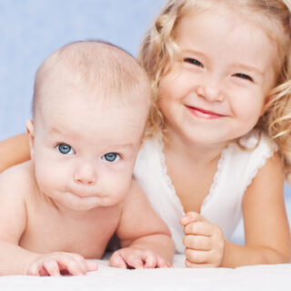 happy little sister hugging her brother lying
